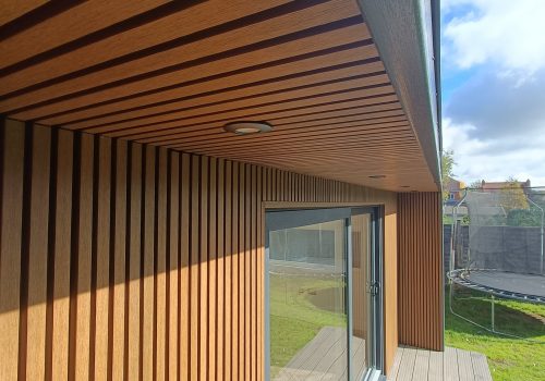 Close-up of vertical timber cladding and soffit detail on a modern garden room exterior with decked platform